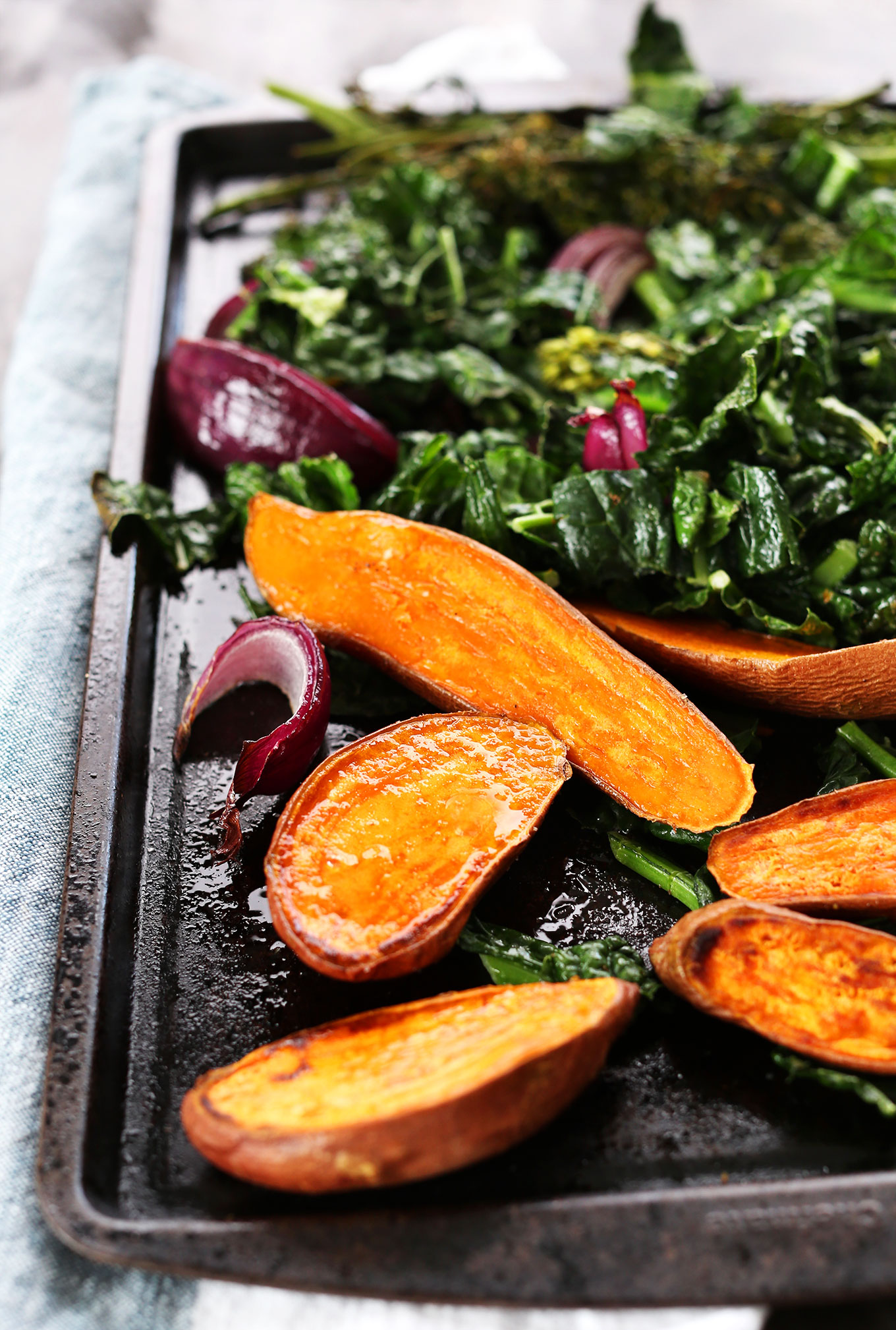 Baking sheet with sweet potatoes and greens for making vegan Buddha Bowls