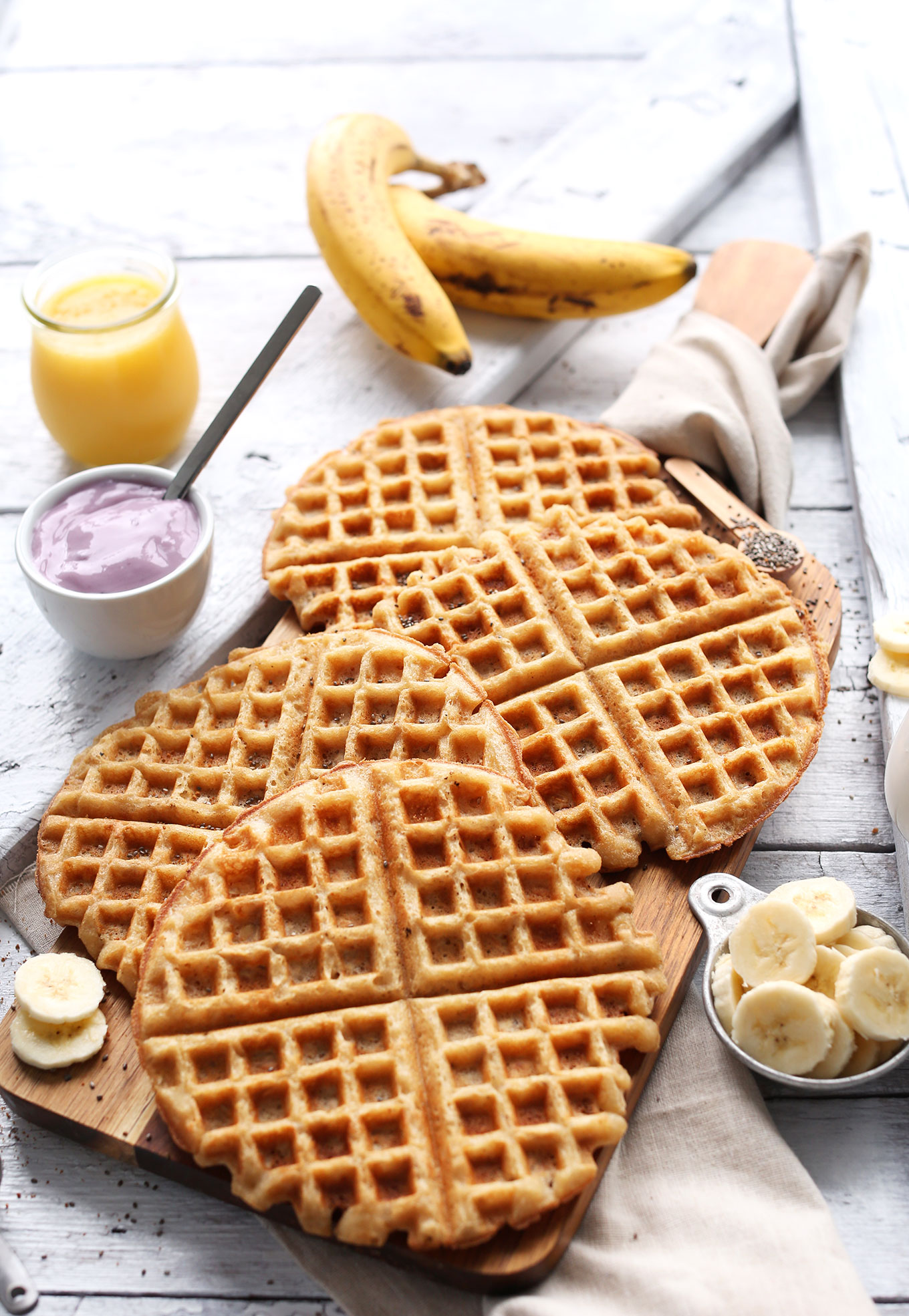 Homemade Yogurt Waffles alongside fresh bananas, yogurt, and orange juice