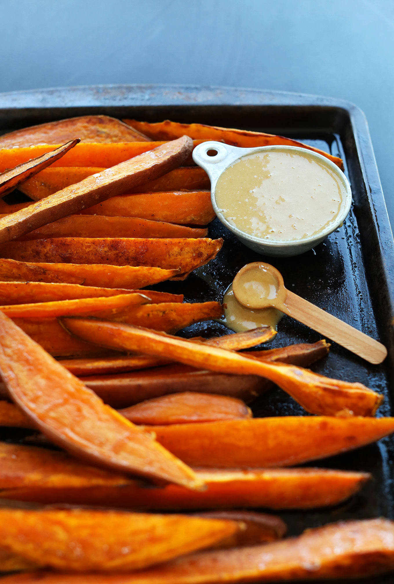 Baking sheet with baked sweet potatoes and delicious vegan No-Honey Mustard Dipping Sauce