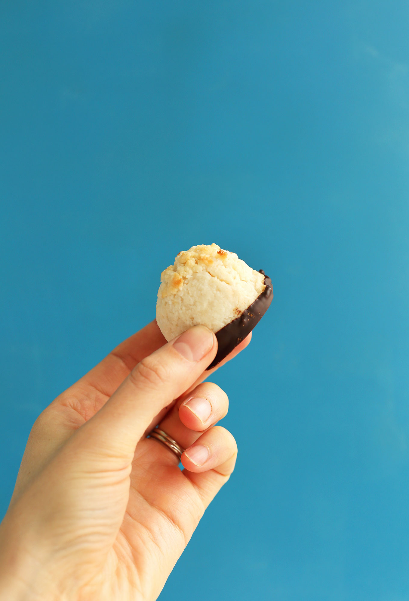 Holding up a delicious gluten-free vegan Dark Chocolate Dipped Coconut Macaroon
