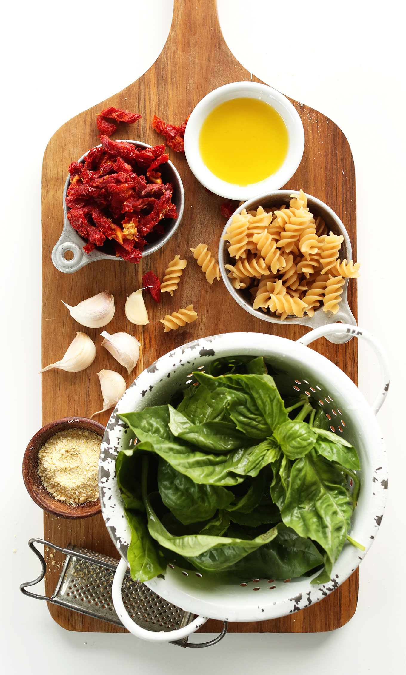 Wood platter with sun-dried tomatoes, olive oil, gluten-free fusili, garlic, basil, and nutritional yeast