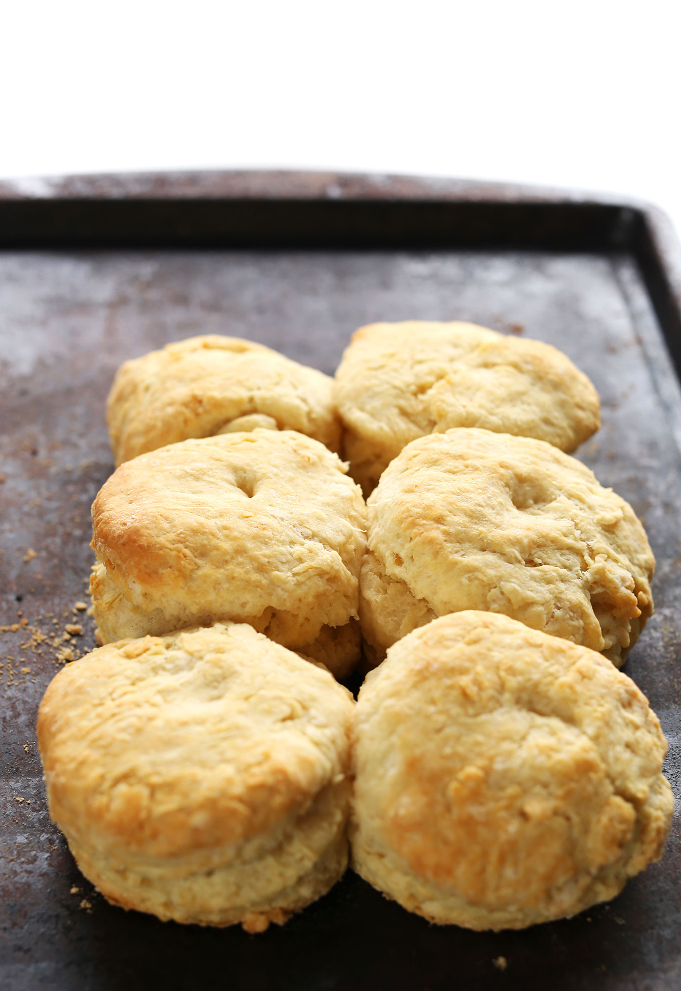 Baking sheet with six freshly baked flaky vegan biscuits