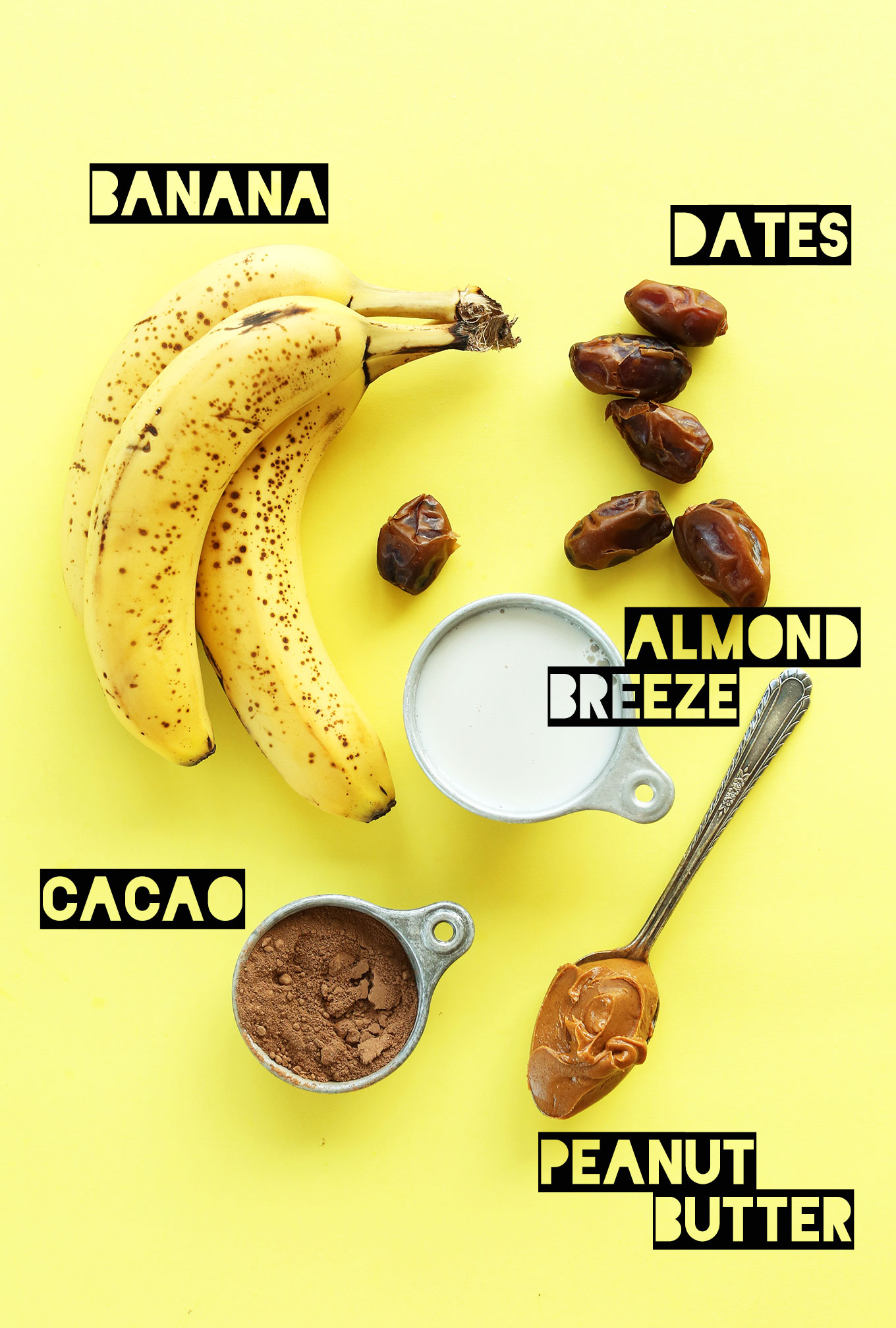 Bananas, dates, almond milk, cacao powder, and peanut butter for making a homemade vegan milkshake