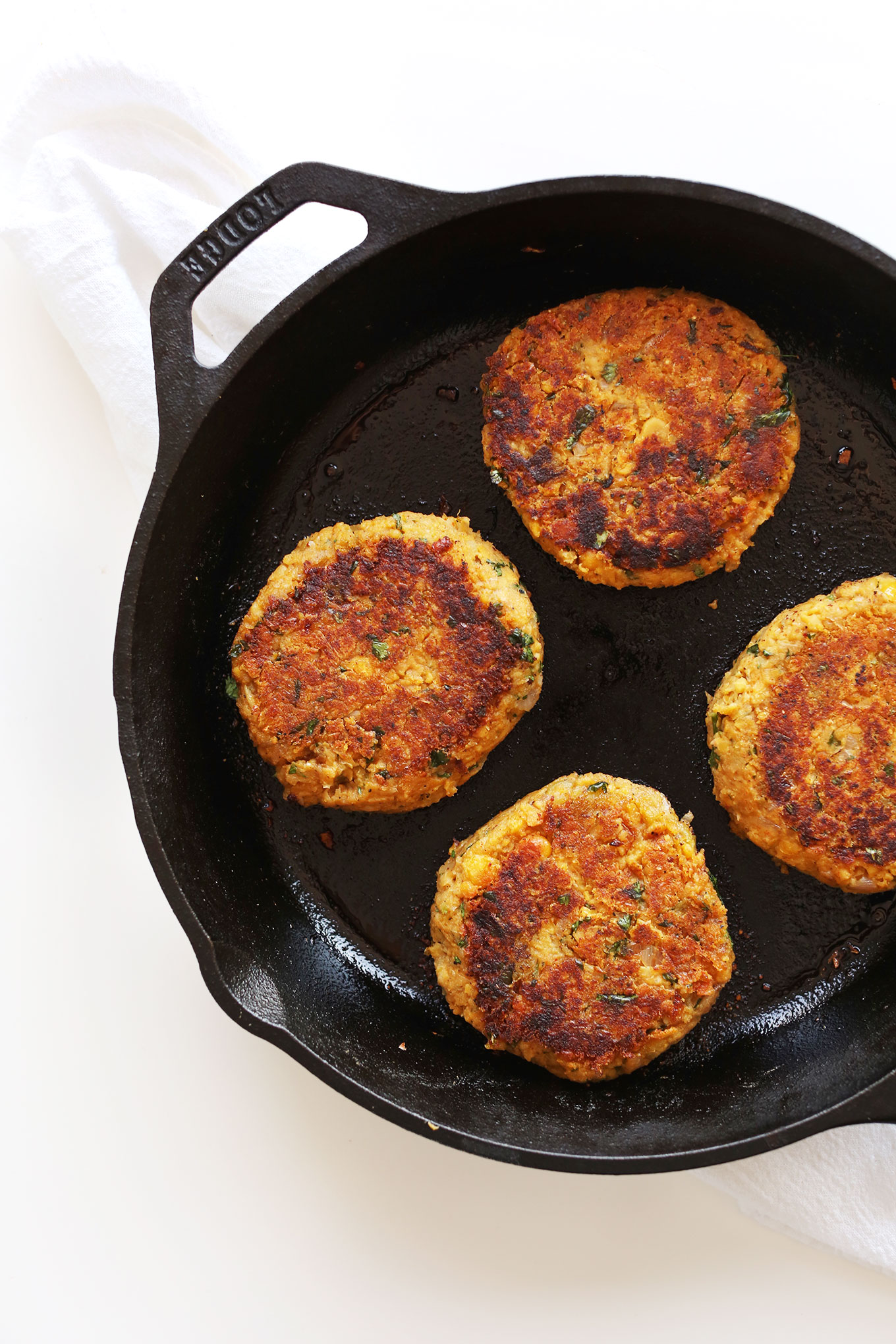 Cast-iron skillet filled with perfectly browned Green Chili Veggie Burgers for a vegan dinner