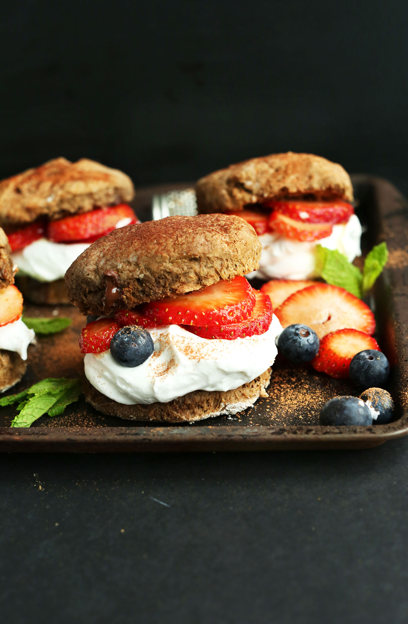 Stack of our flaky vegan Double Chocolate Shortcakes with coconut whipped cream and fresh berries