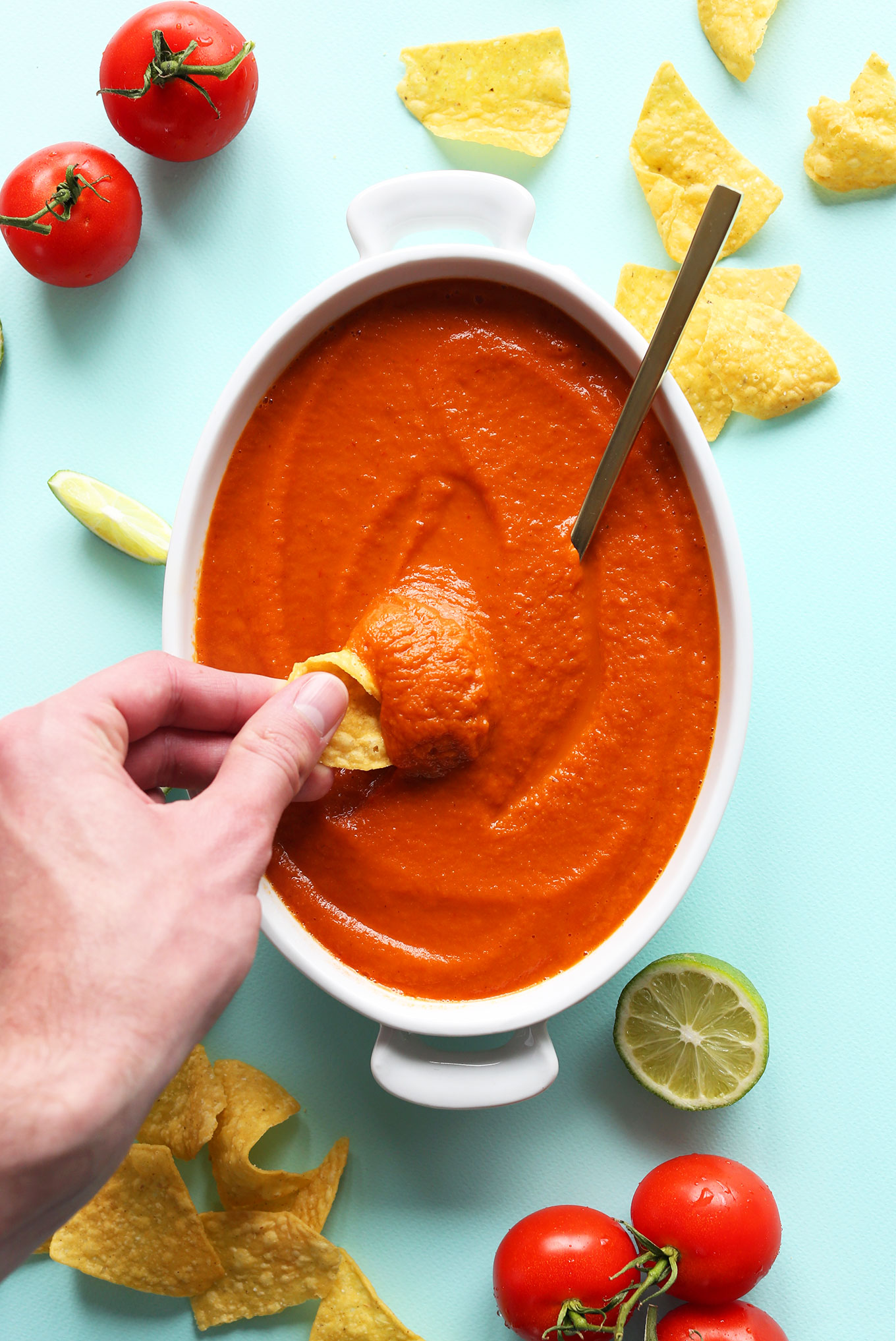 Dipping a tortilla chip into creamy vegan homemade Red Salsa