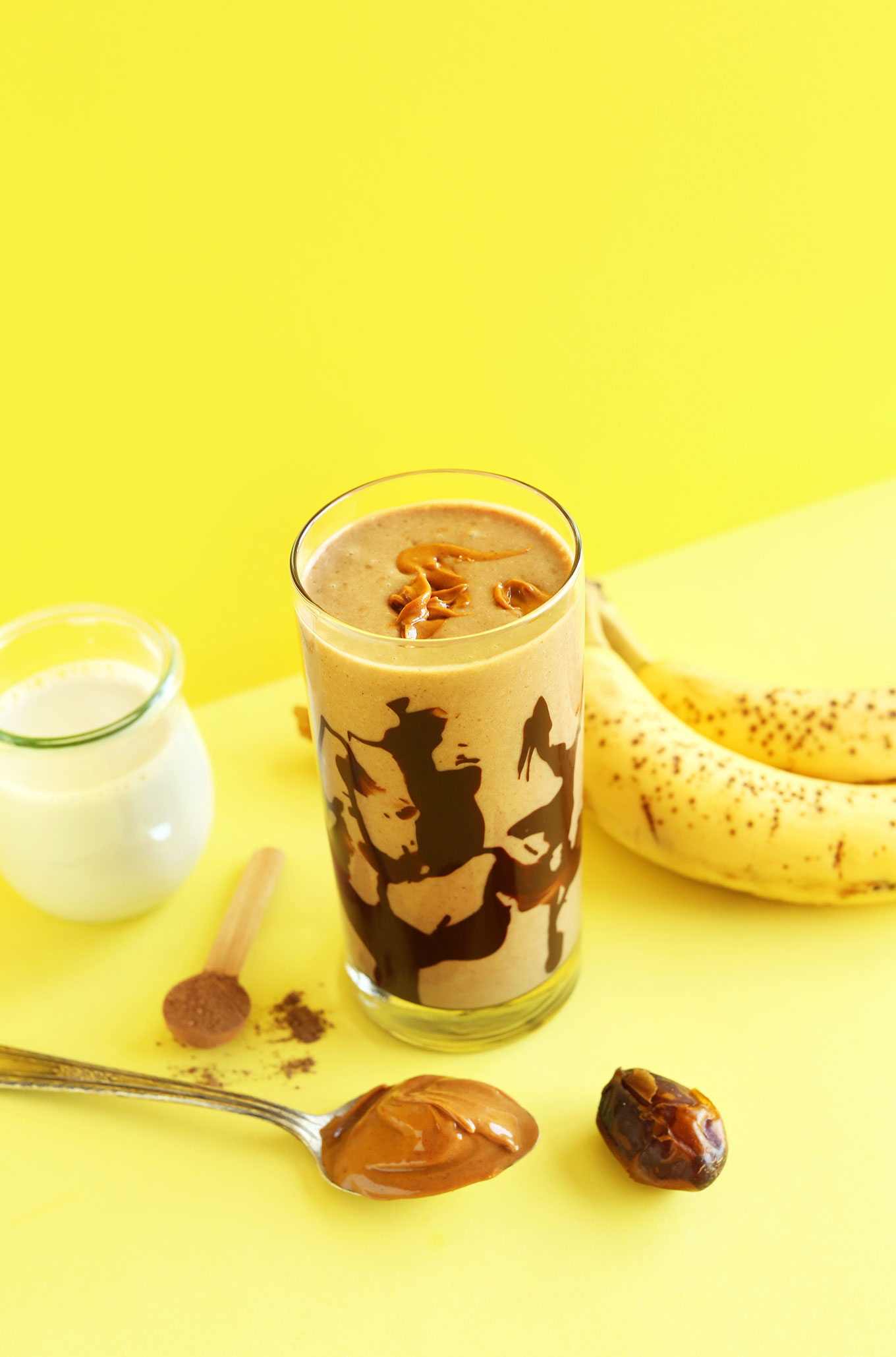 Creamy vegan Peanut Butter Chocolate Shake surrounded by ingredients used to make it