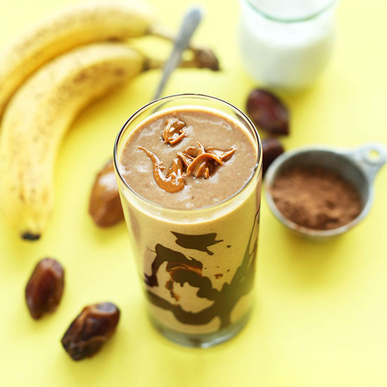 Tall glass of our PB Banana Shake surrounded by ingredients to make it