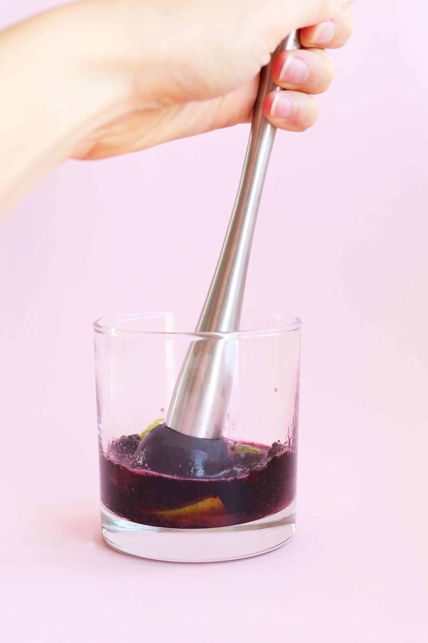 Muddling blackberries and limes for a homemade summer mojito recipe