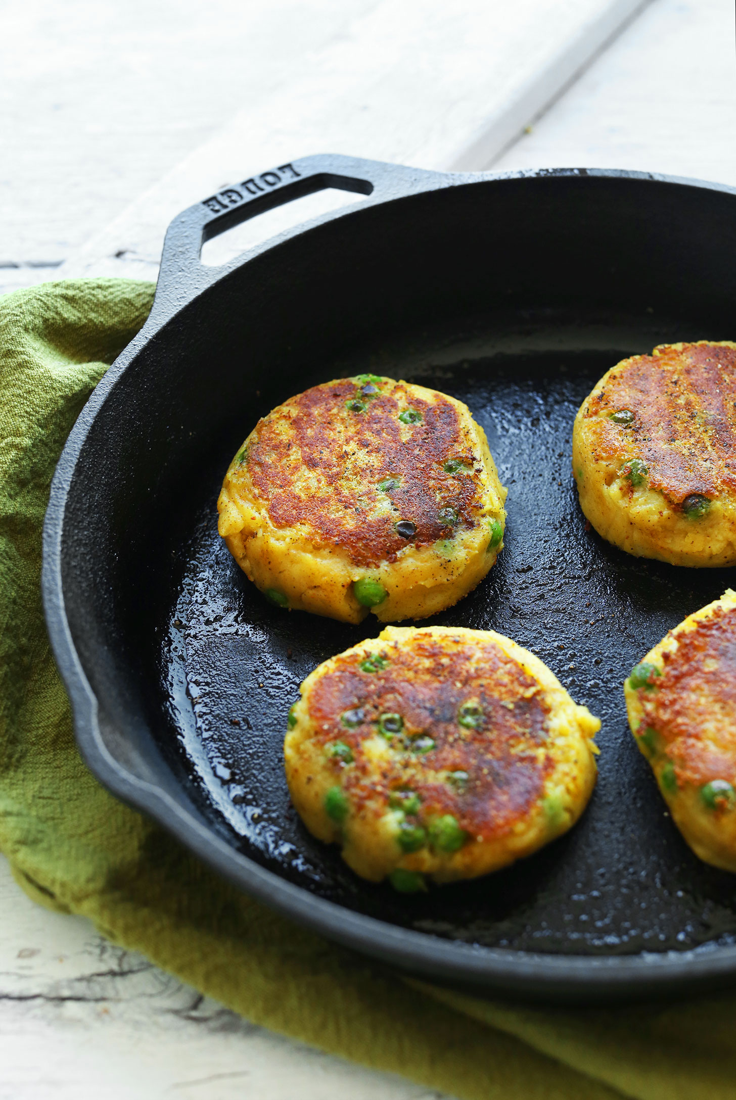 Cooking gluten-free vegan Samosa Potato Cakes in a cast-iron skillet
