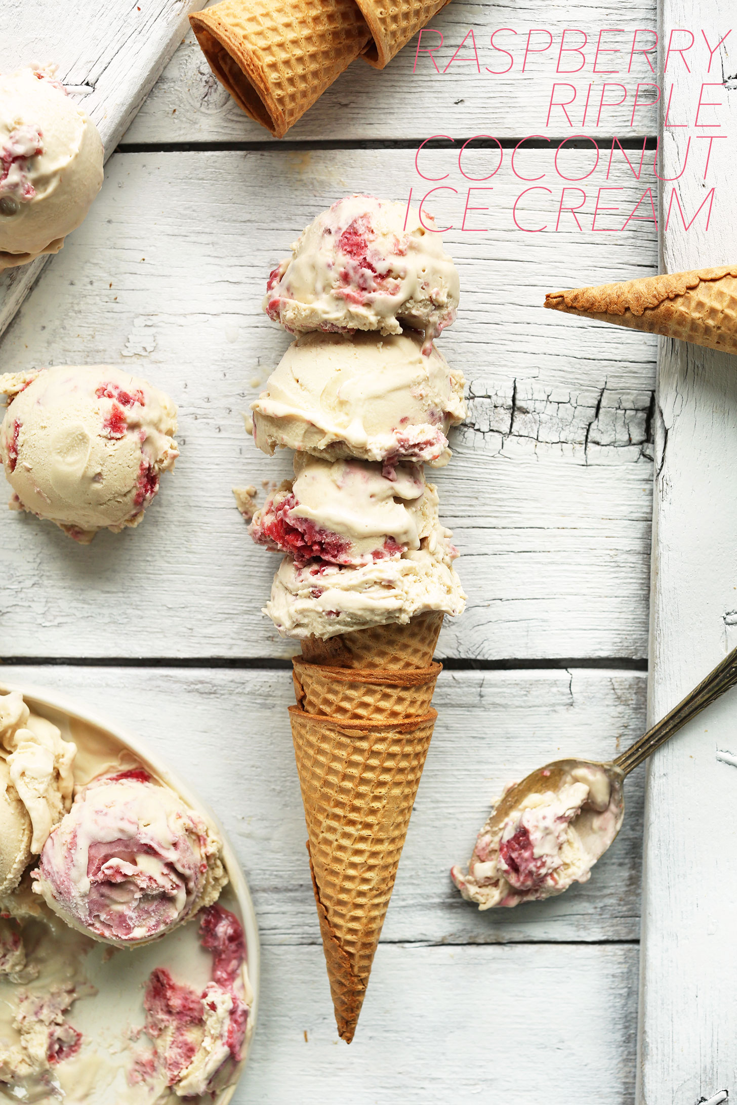 Scoops of homemade Raspberry Coconut Ice Cream piled high on a sugar cone
