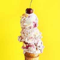 Scoops of Cherry Pie Ice Cream topped with a fresh cherry