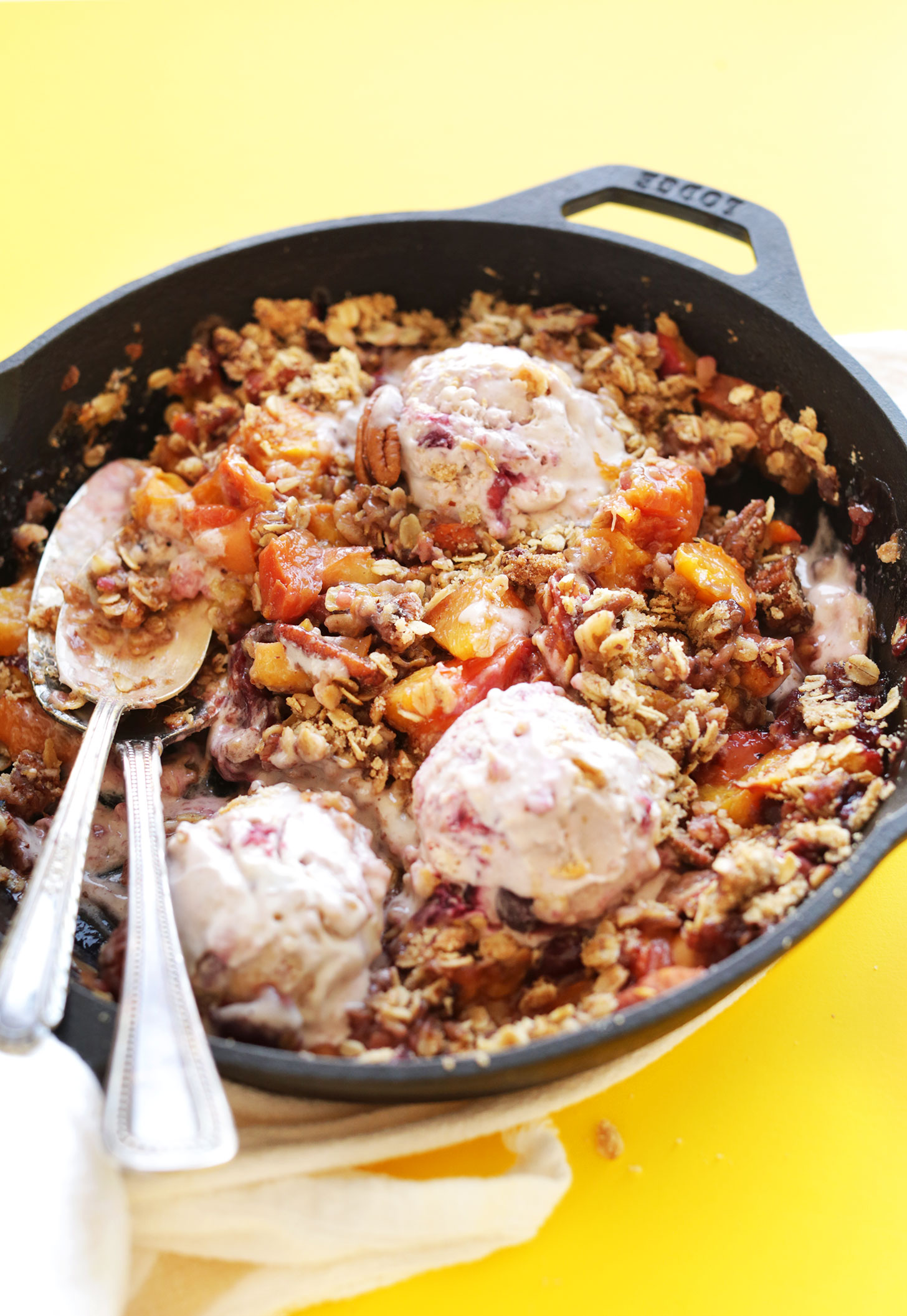 Spoons in a cast-iron skillet for eating our Summer Peach Crisp with dairy-free ice cream