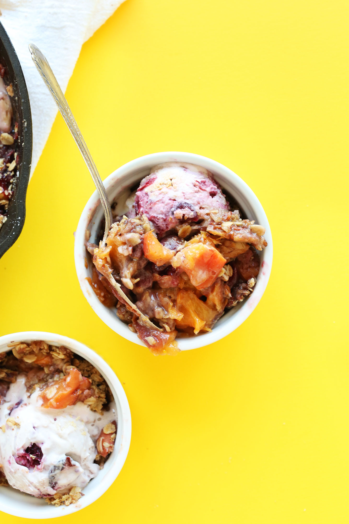 Ramekins filled with gluten-free vegan Summer Peach Crisp with vegan ice cream