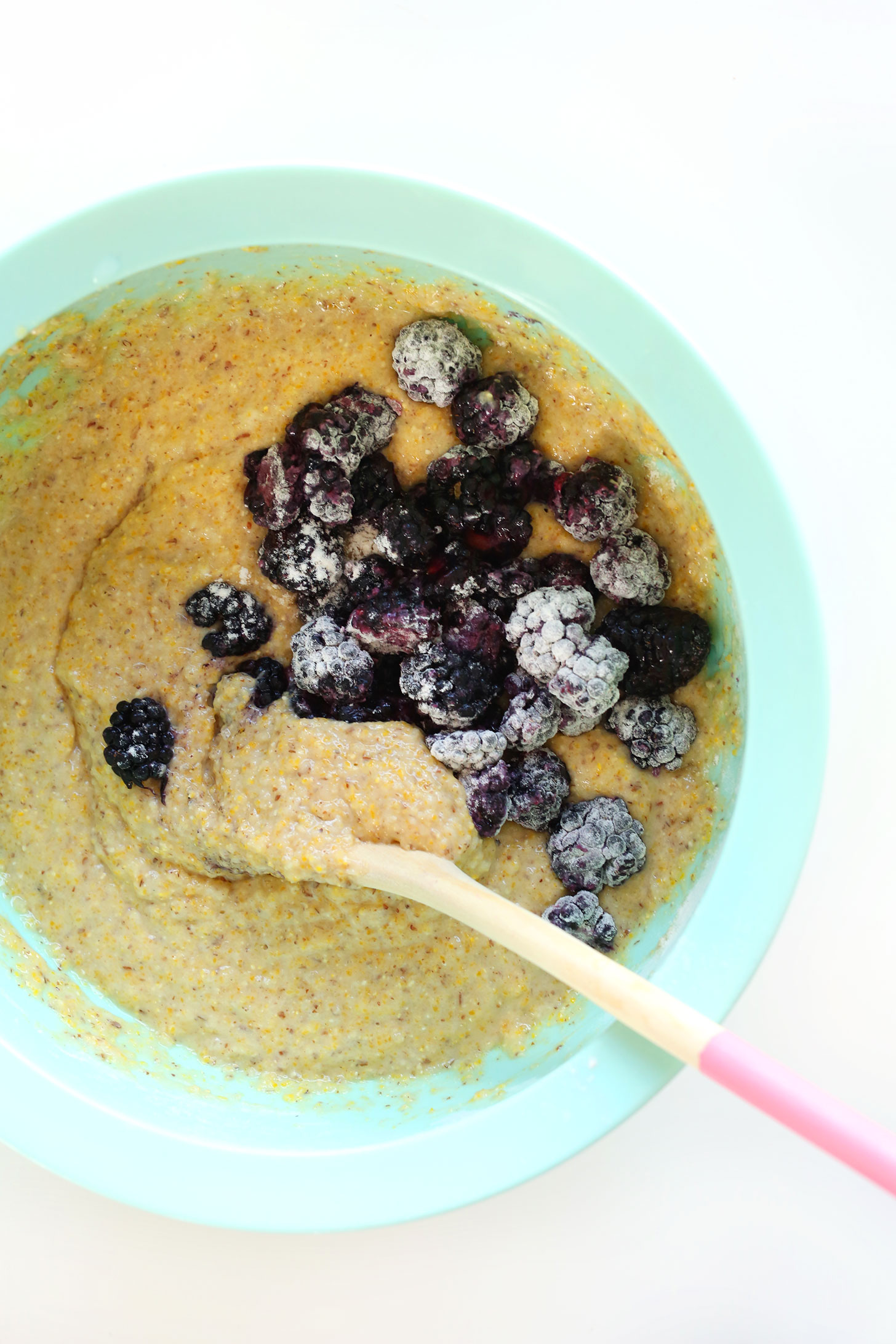 Stirring blackberries into batter for our vegan Blackberry Cornmeal Muffins recipe