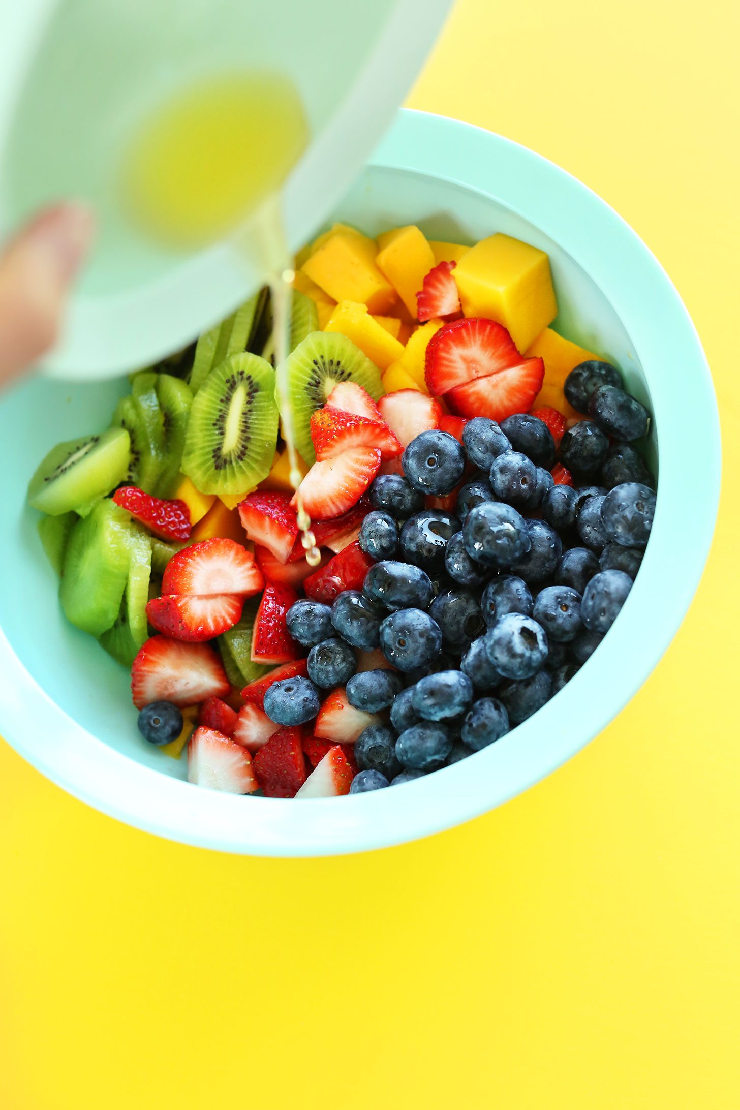 Pouring lime juice onto our amazing vegan Spicy Fruit Salad recipe