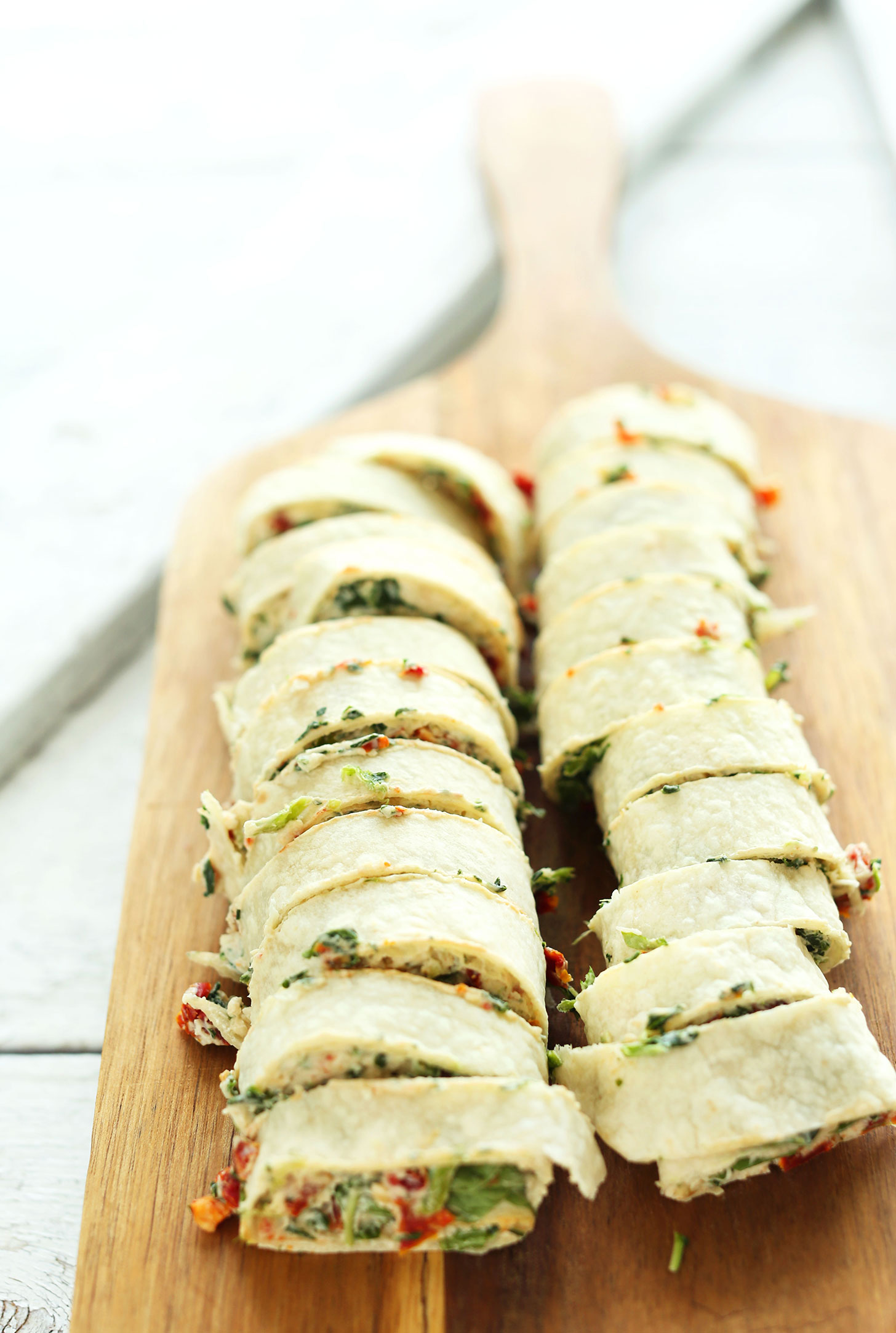 Cutting board filled with freshly sliced Sun-Dried Tomato Basil Pinwheels