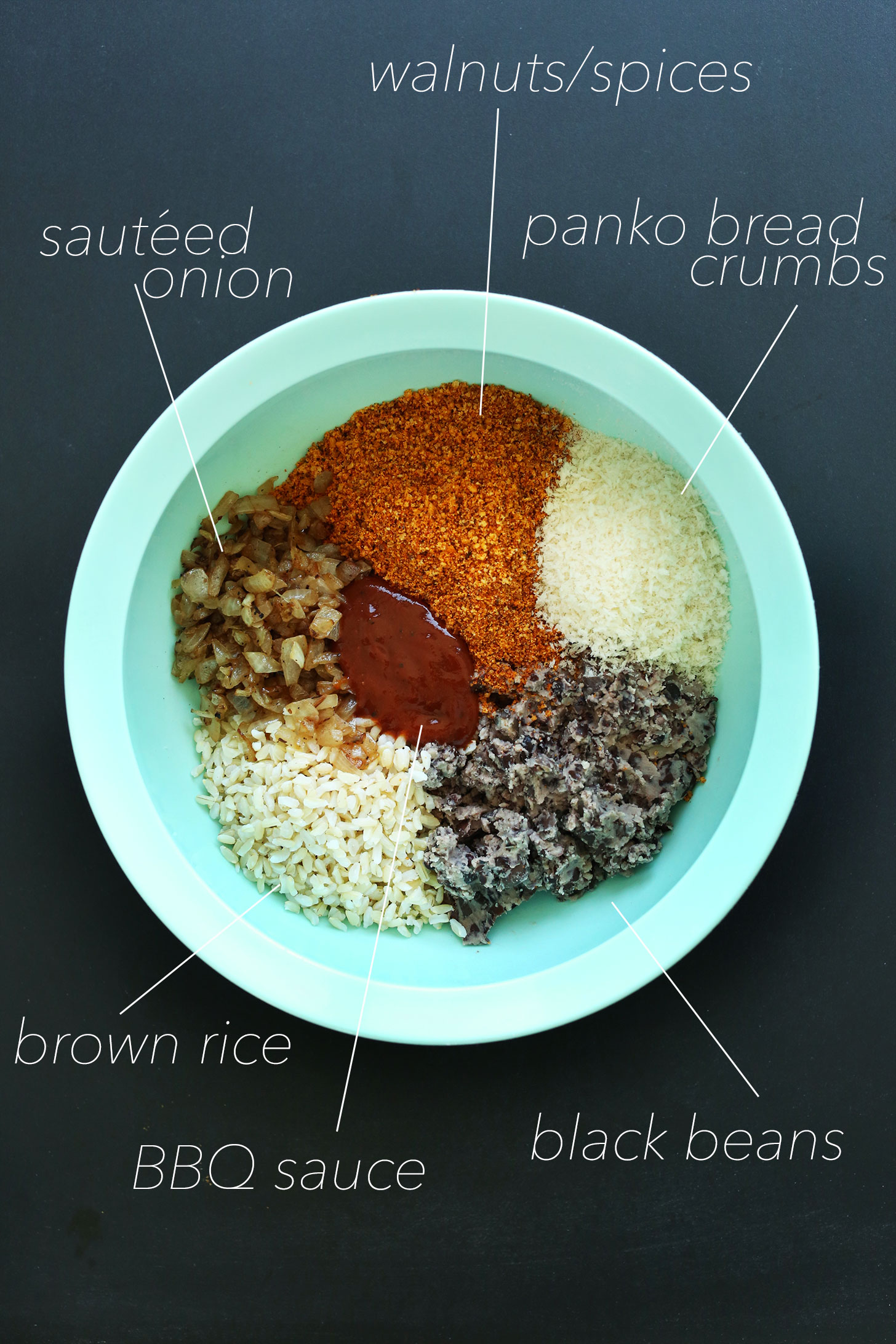 Bowl of walnuts, spices, bread crumbs, black beans, BBQ sauce, brown rice, and sautéed onions for making homemade veggie burgers