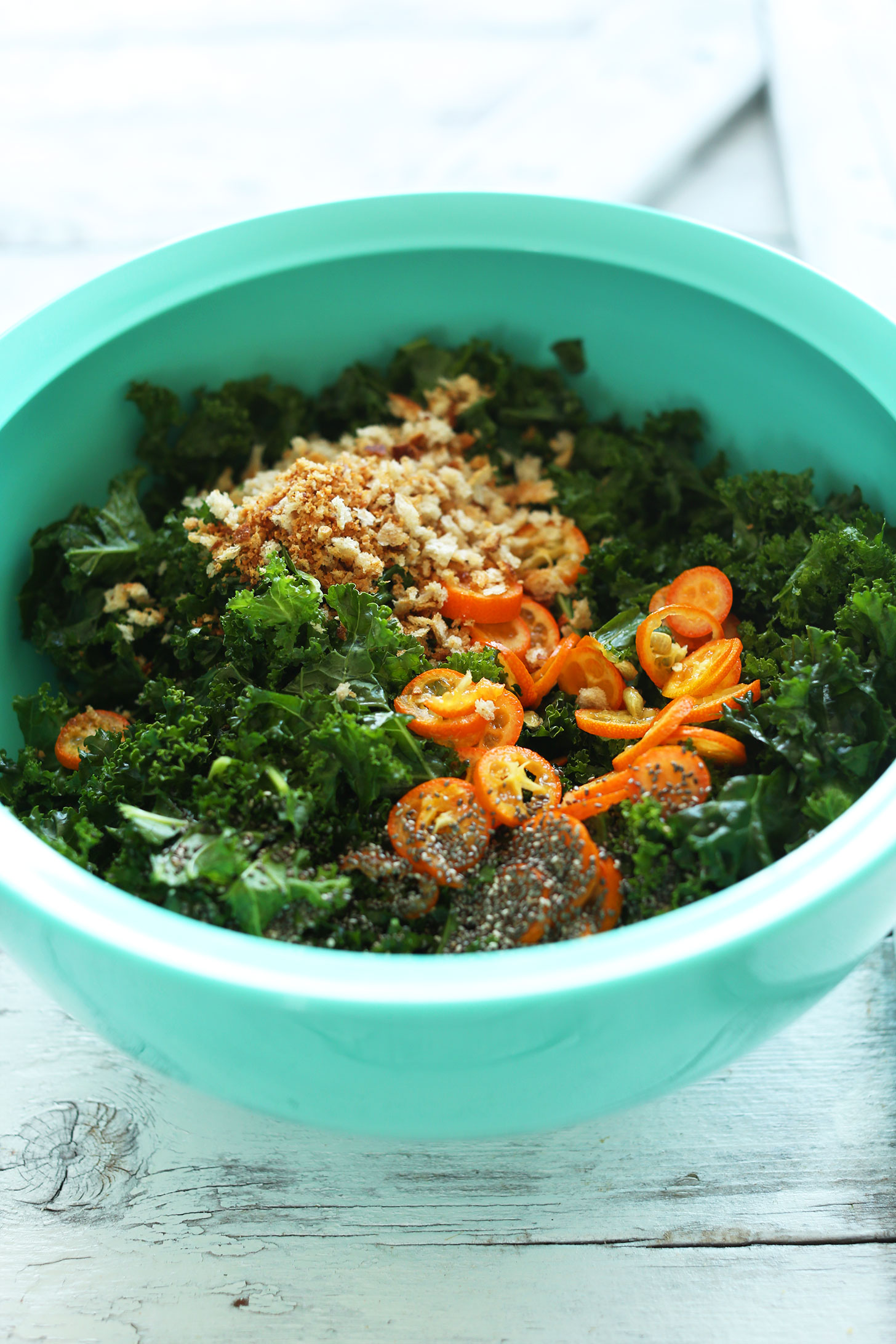 Big bowl of vegan Kale Salad with Kumquats, Chia Seeds, and Breadcrumbs
