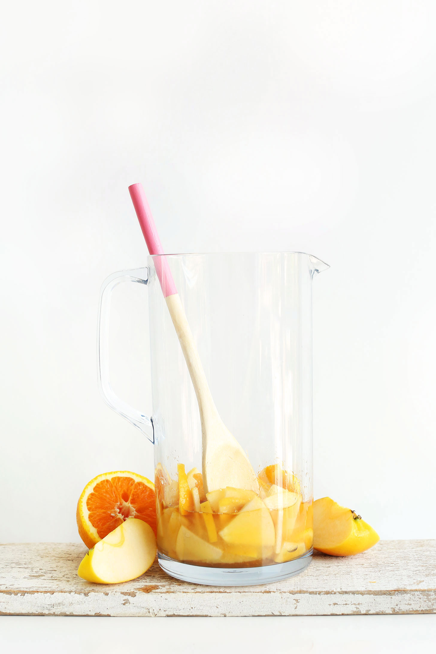 Using a wooden spoon to muddle fruit with orange juice and brandy for Traditional Sangria