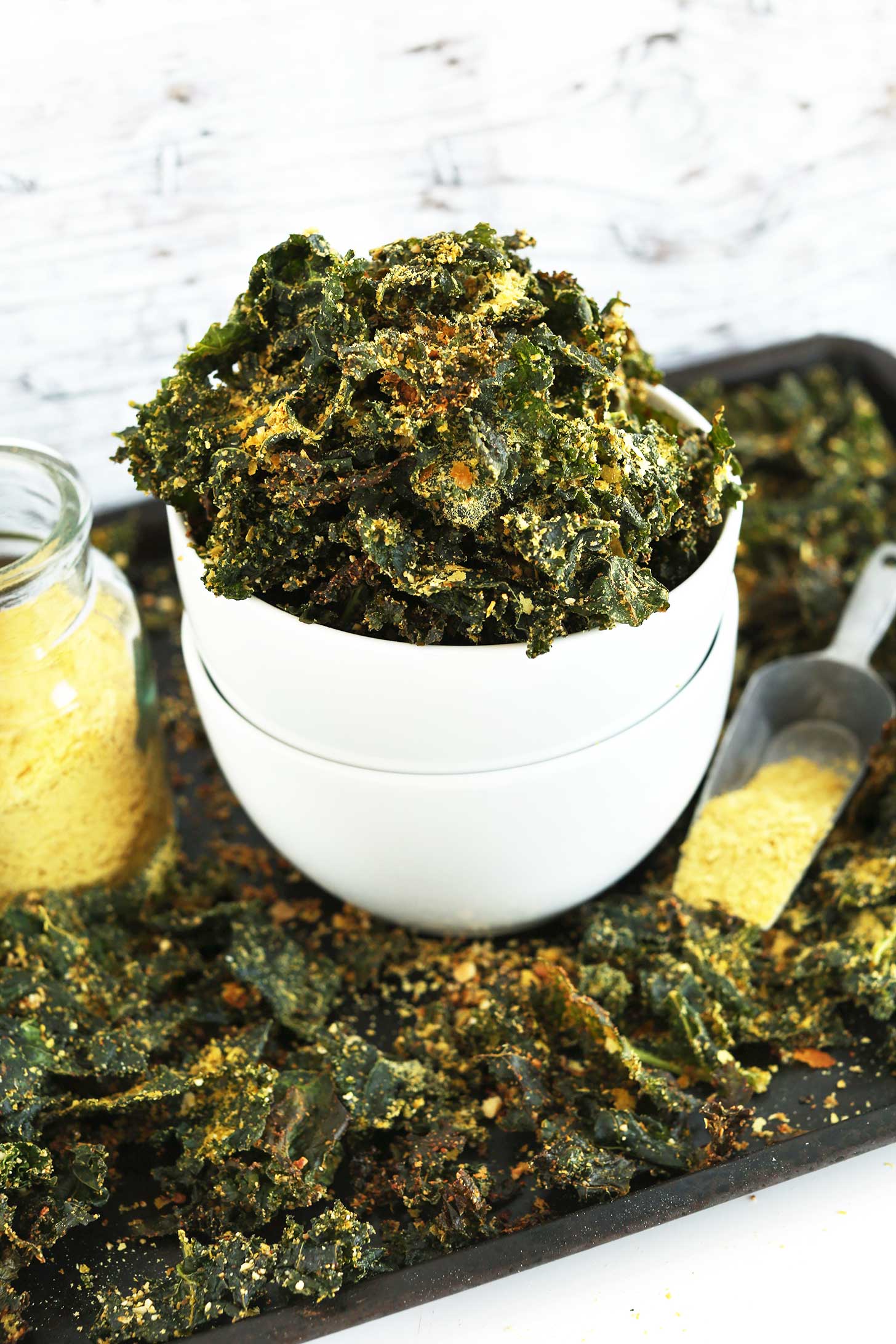 Bowl of our easy to make Cheesy Vegan Kale Chips on a baking sheet