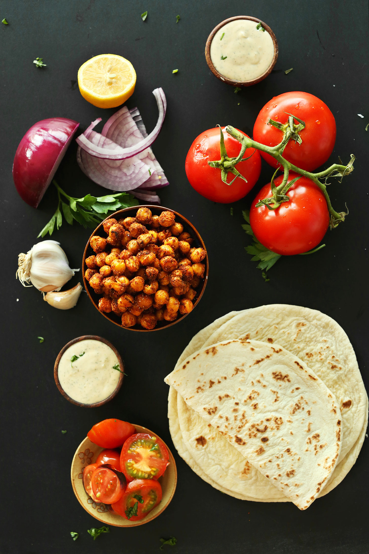 Tomatoes, Shawarma-Spiced Chickpeas, red onion, flatbread, and garlic dill sauce for making Healthy Vegan Wraps