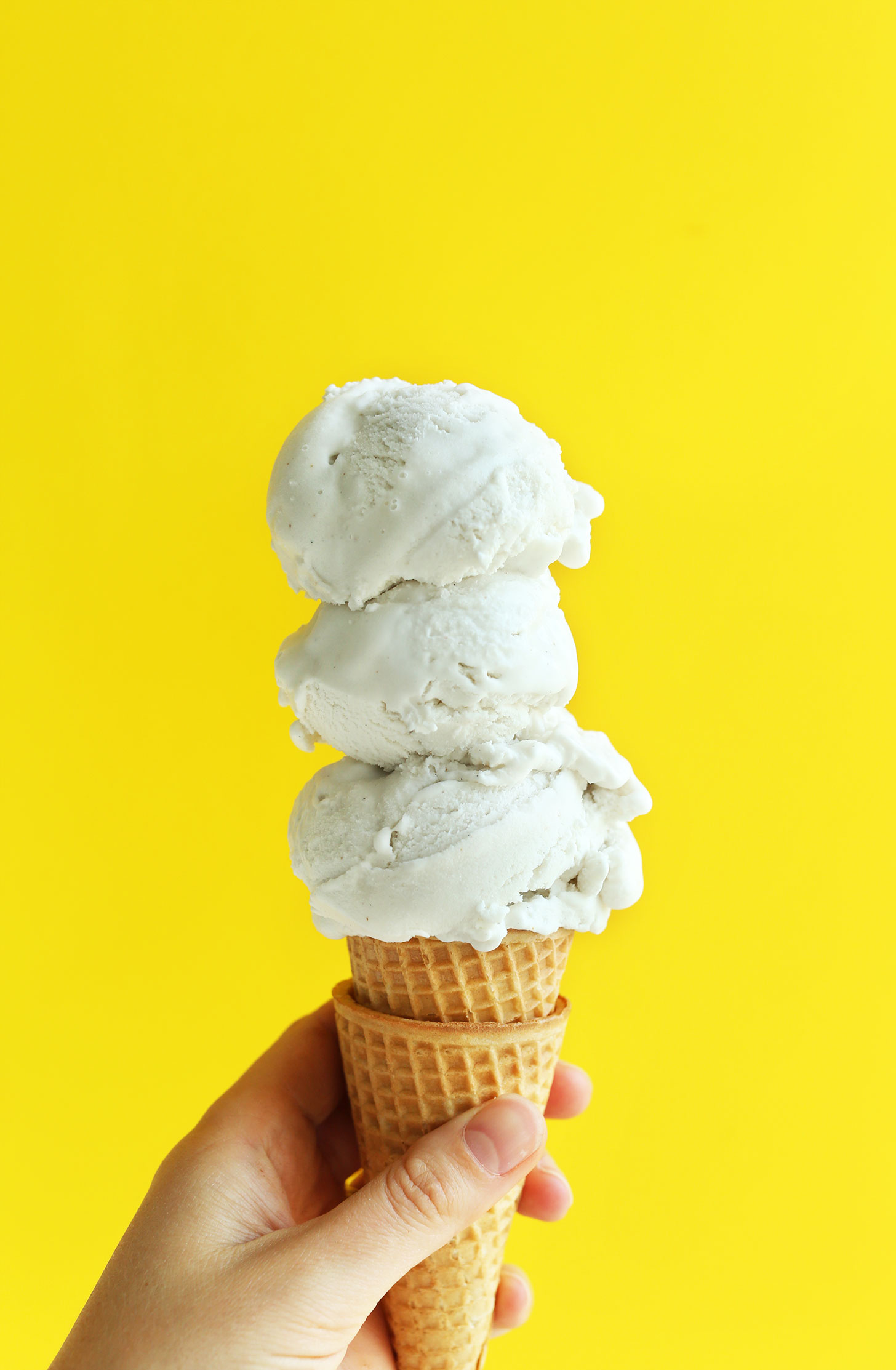 Cone topped with scoops of homemade vegan vanilla coconut ice cream