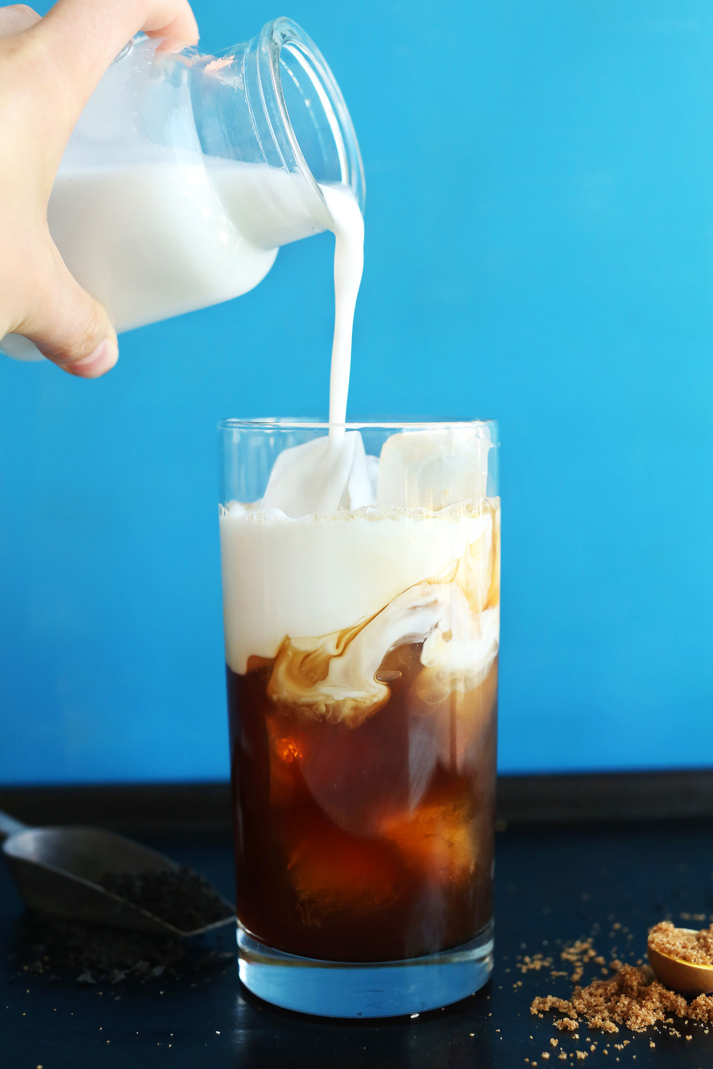 Pouring coconut milk into a glass for simple and delicious Vegan Thai iced Tea