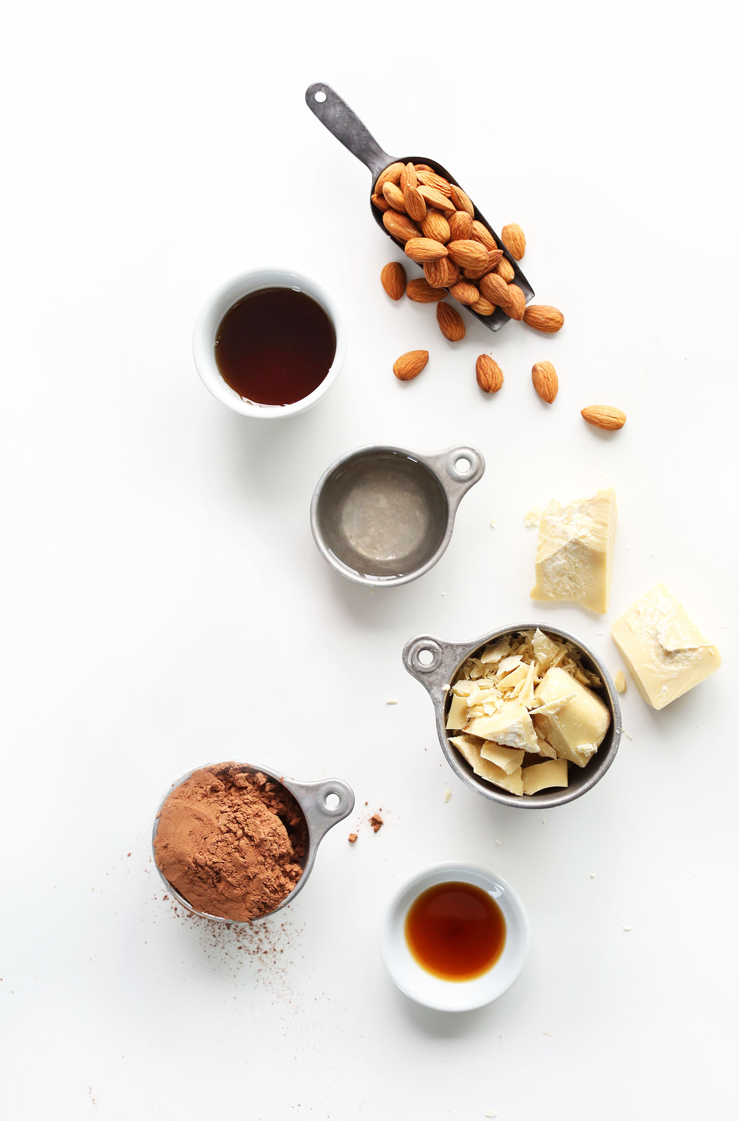 Almonds, maple syrup, coconut oil, cacao butter, cocoa powder and vanilla extract for making vegan Dark Chocolate Almond Bars
