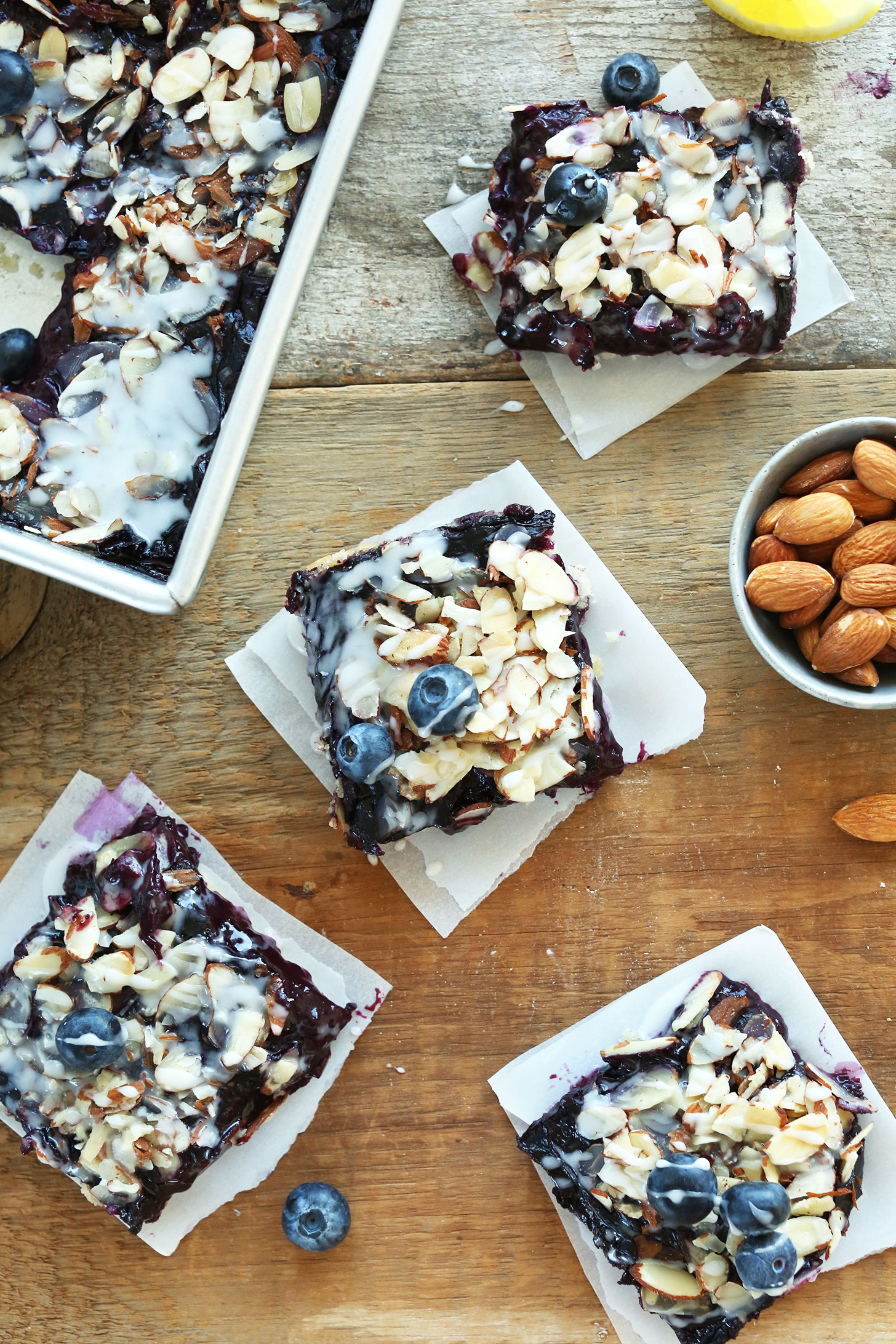 Squares of vegan Almond Blueberry Pie Bars resting on parchment paper cut outs