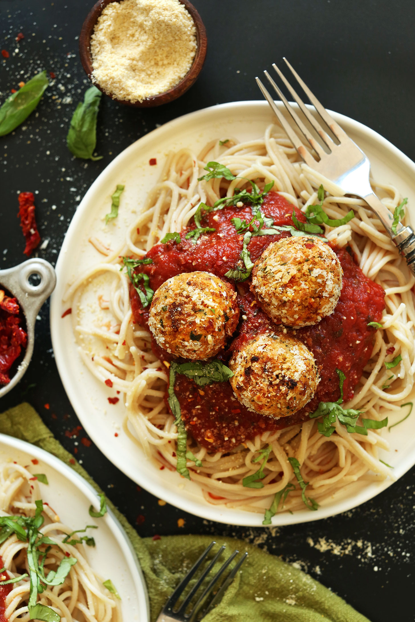 Dinner plate filled with spaghetti noodles, marinara, Vegan Chickpea Meatballs, and fresh basil