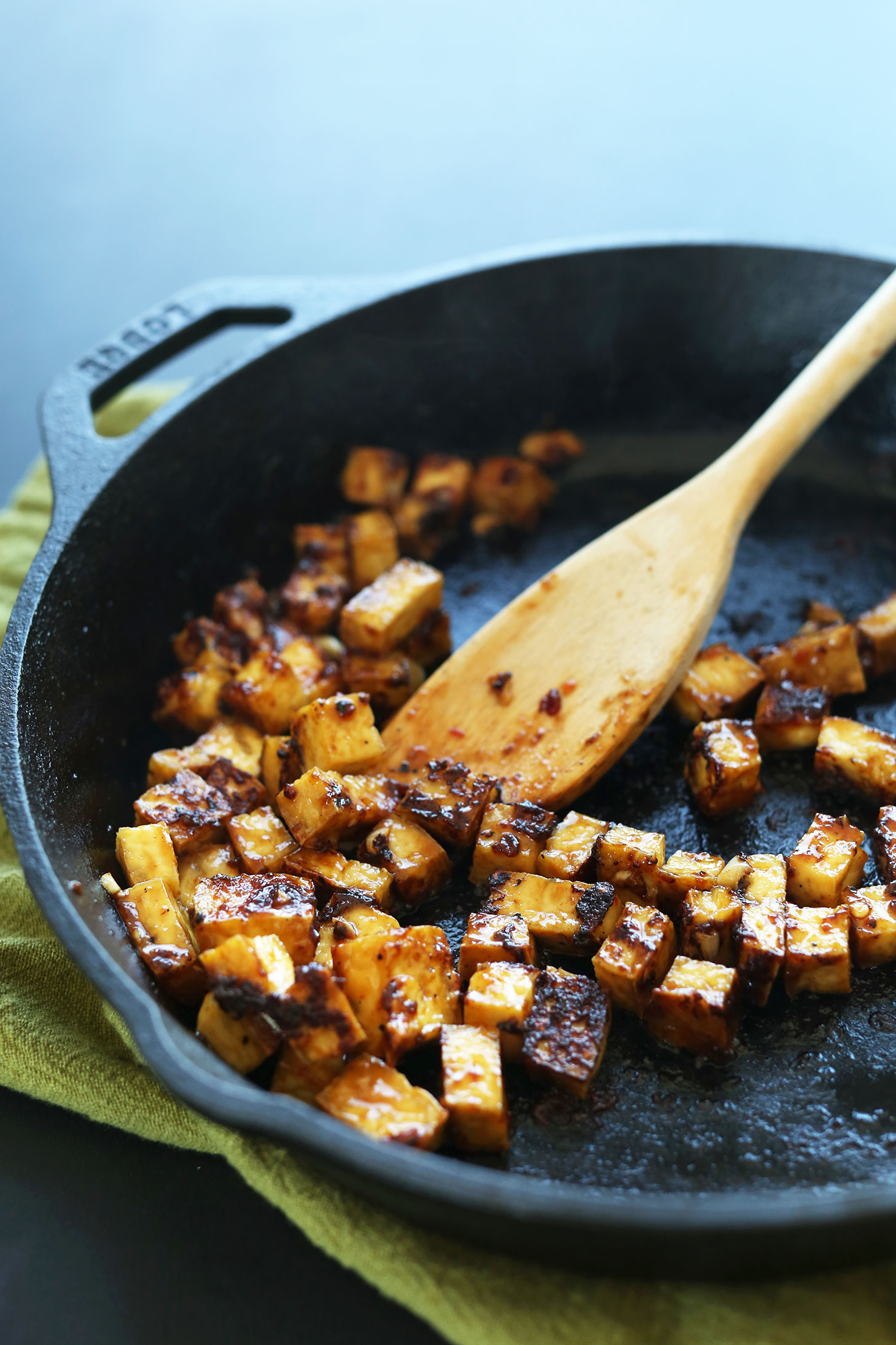 Cooking tofu in a cast-iron skillet for making vegan fried rice