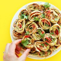 Picking up a Mexican Pinwheel from a plate for a delicious appetizer