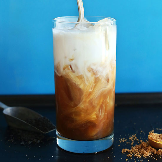 Swirling dairy-free milk into a tall glass of homemade Thai Iced Tea
