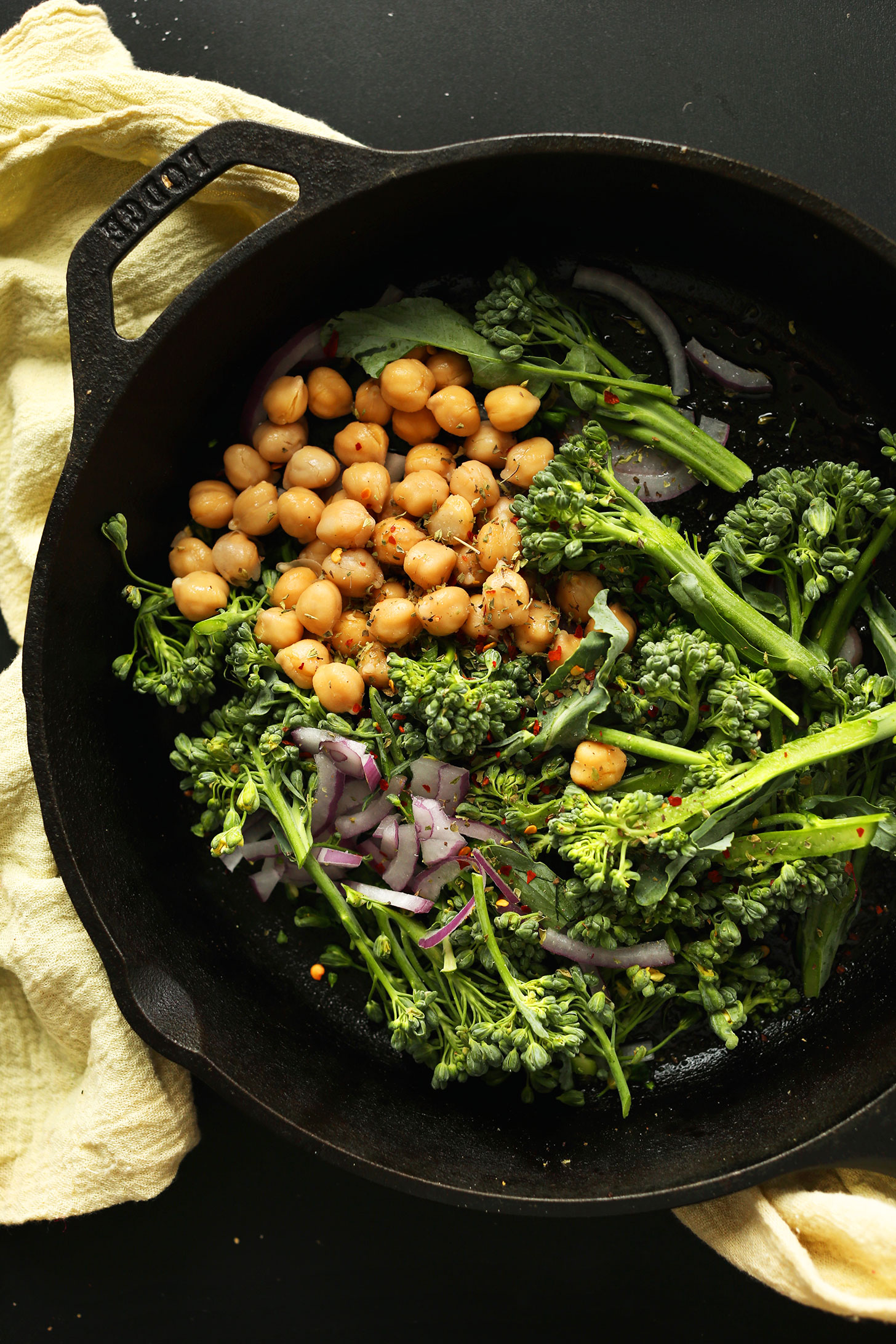 Roasting vegetables and chickpeas in a cast-iron skillet for making healthy vegan pizza