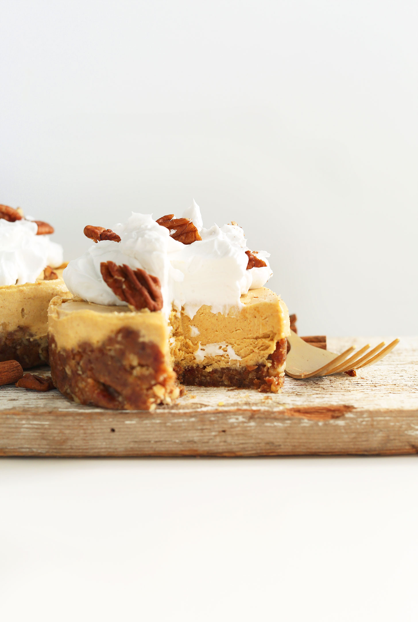 A mini Vegan Pumpkin Cheesecake topped with coconut whipped cream and pecans