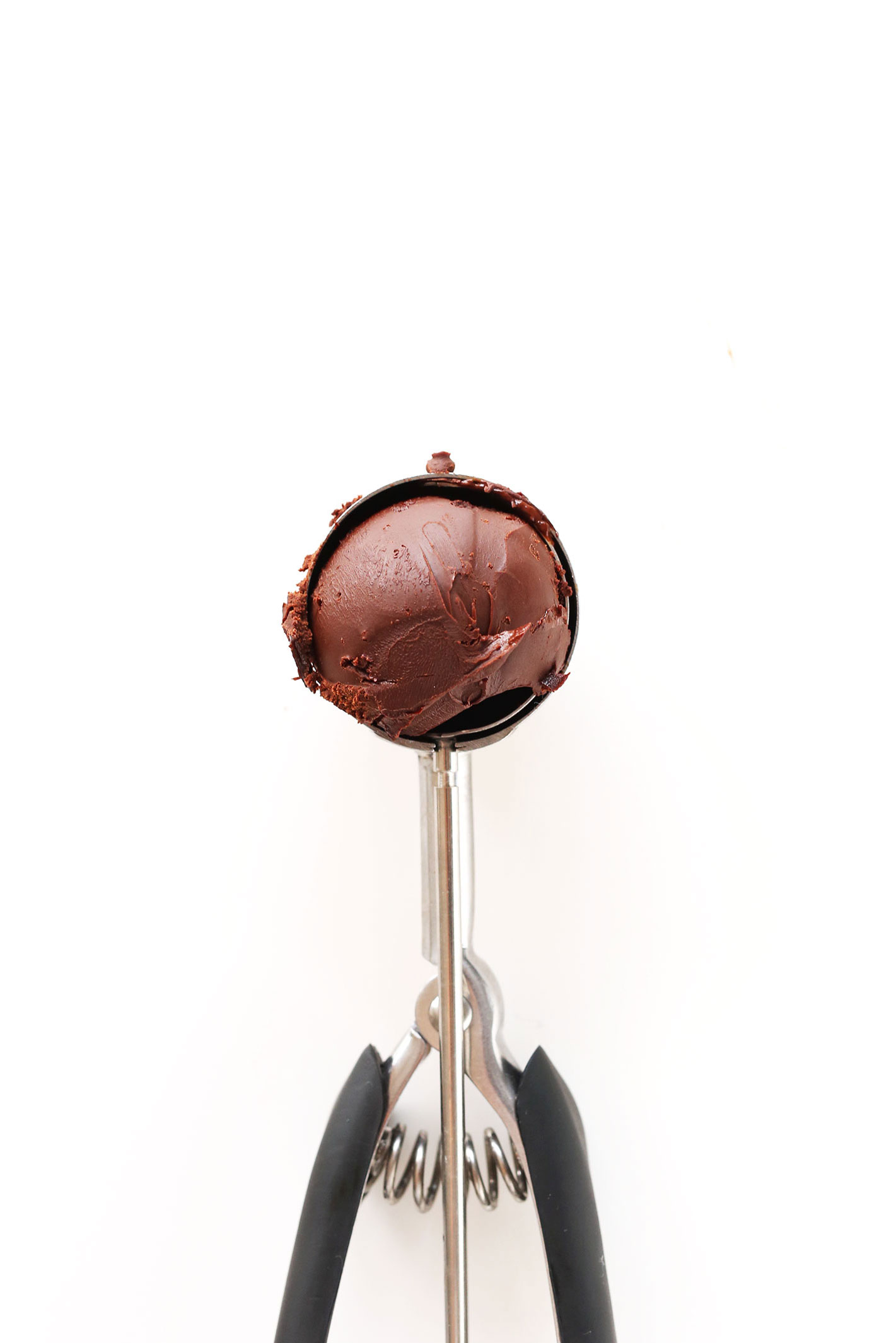 Using a cookie scooper to scoop up batter for making Vegan Dark Chocolate Truffles