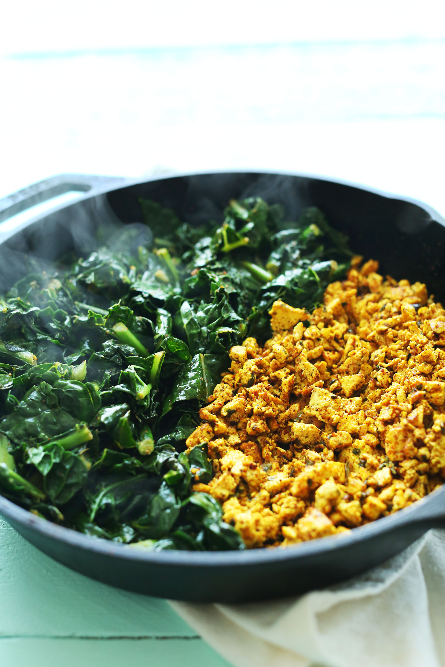 Cooking kale and tofu in a cast-iron skillet for our Savory Tofu Scramble recipe