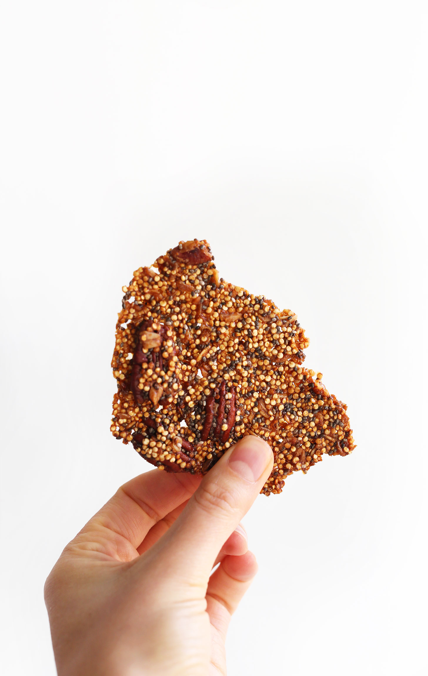 Holding up a piece of our naturally-sweetened vegan Quinoa Brittle