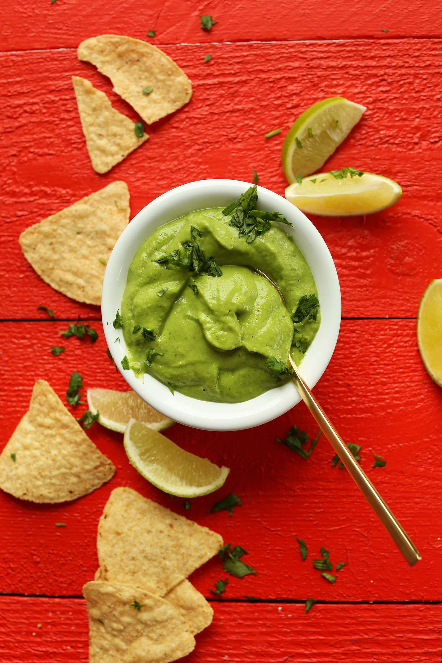 Bowl of our creamy avocado cilantro dressing surrounded by tortilla chips and limes