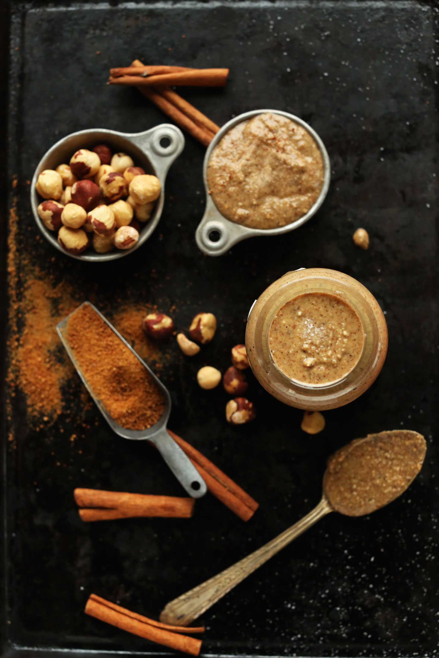 Baking sheet with hazelnuts, cinnamon, and coconut sugar for making a jar of homemade hazelnut butter