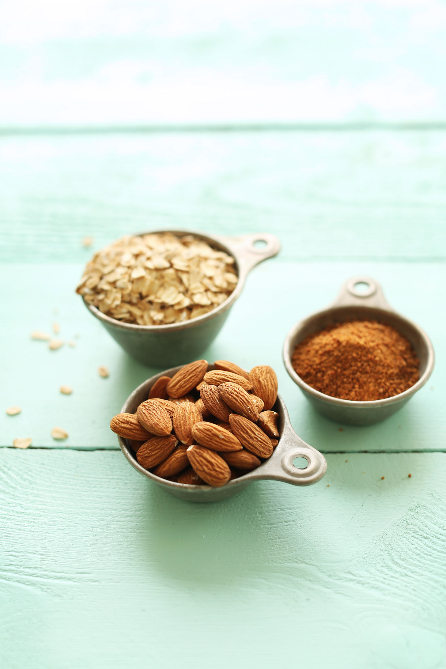 Measuring cups of oats, almonds, and coconut sugar for making Vegan PB&J Bars