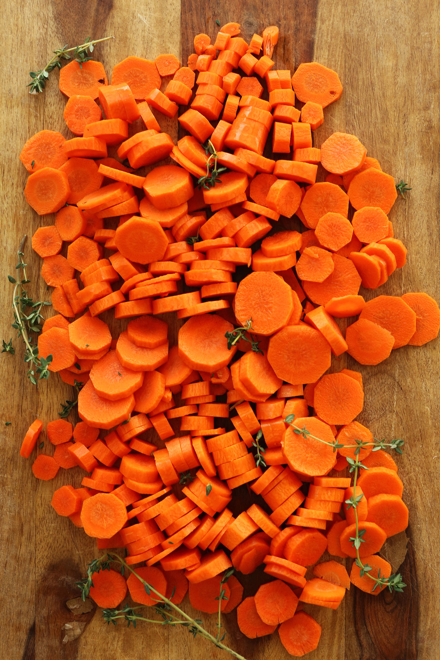 Peeled and sliced carrots surrounded by sprigs of fresh thyme