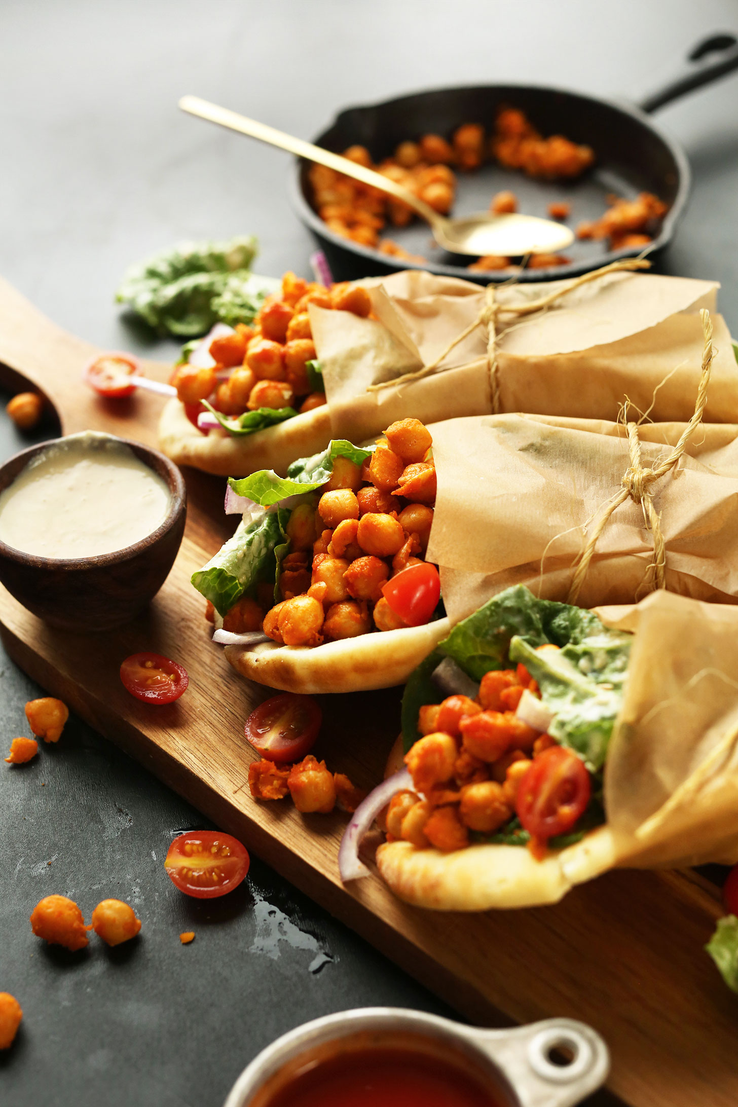 Rolled vegan Buffalo Chickpea Wraps with a side of creamy hummus dressing