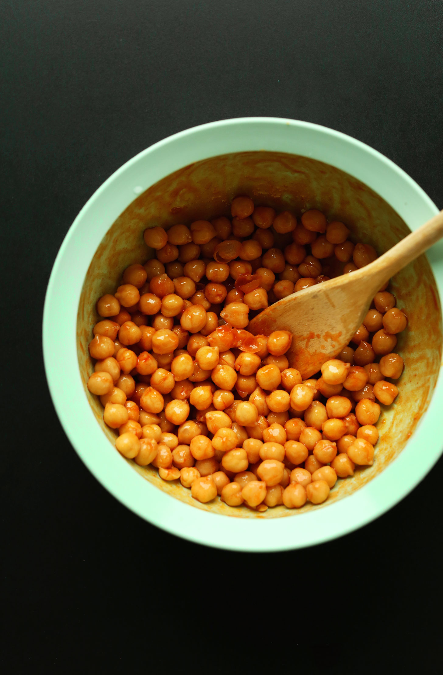 Stirring buffalo-style sauce onto chickpeas for a protein-packed vegan meal