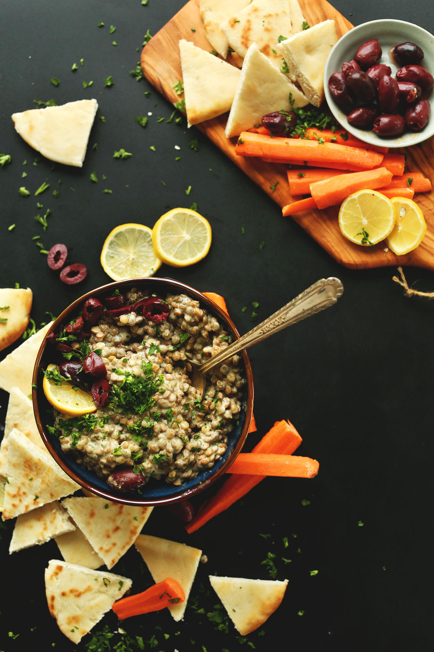 Bowl of our delicious Mediterranean Lentil Dip recipe alongside pita bread and carrot sticks for dipping