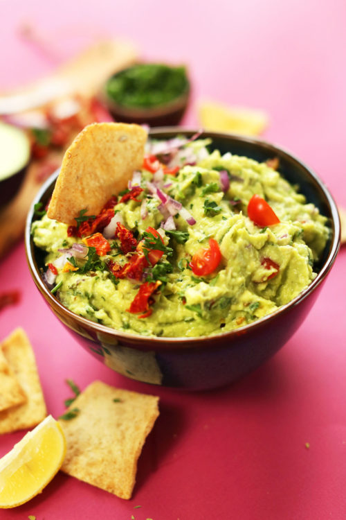Dipping a cracker into our delicious plant-based Greek-Inspired Guacamole recipe