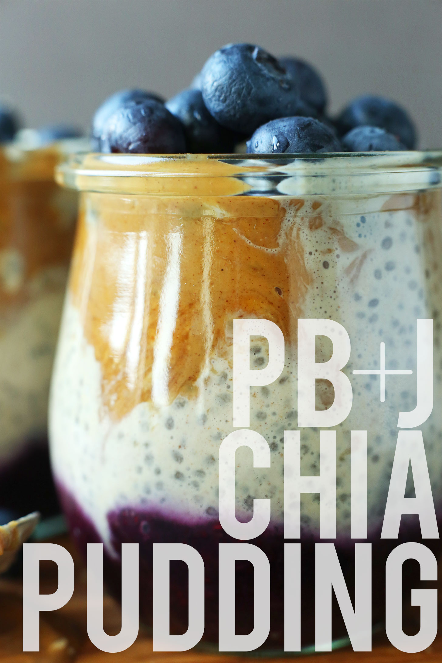 Close up shot of a jar of Peanut Butter and Jelly Chia Pudding topped with fresh blueberries