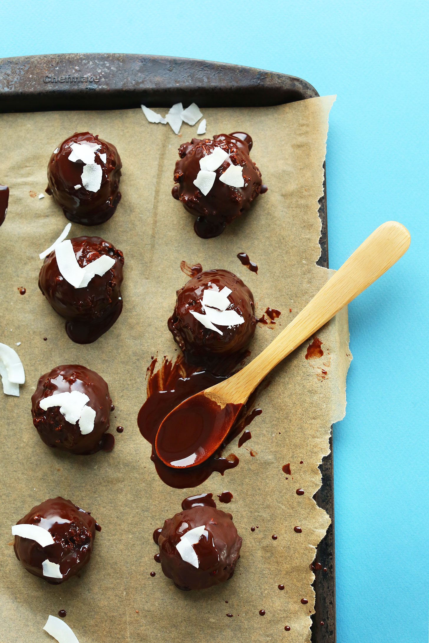 Parchment-lined baking sheet with macaroons freshly coated with vegan chocolate sauce