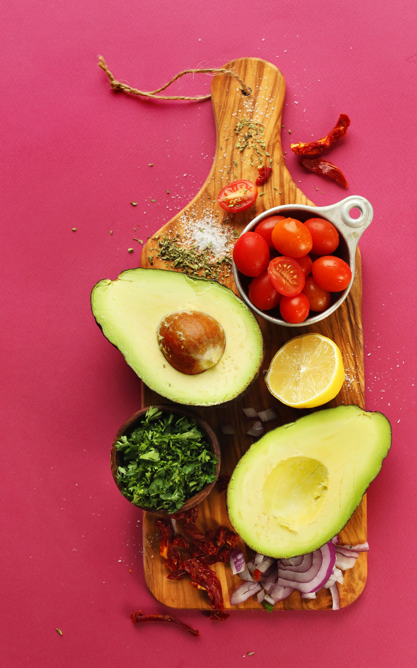 Avocado, sun-dried tomatoes, parsley, lemon, red onion, tomatoes, oregano, and spices for making Greek-Inspired Guacamole